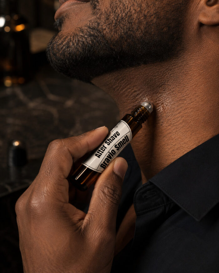 mão esquerda aplicando after shave com frasco cilíndrico de vidro âmbar com ponta de esfera deslizante no pescoço
