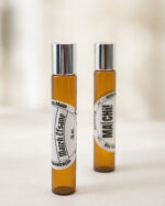 dois frascos de perfume cor âmbar com tampas cromadas posicionados um na frente e outro ao fundo com respectivos adesivos redondos brancos match efsane e o do fundo matchii