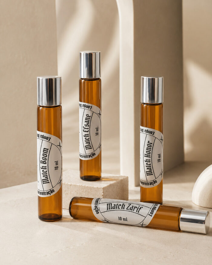 quatro frascos cilíndricos de perfume portátil feitos com vidro âmbar rótulos redondos brancos e tampas prateadas três na posição vertical e um na horizontal sob pedra de granito clara
