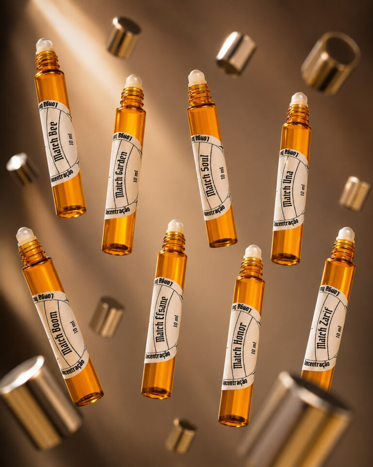 oito frascos cilíndricos de perfume portátil feitos de vidro âmbar com tampas prateadas flutuando dispostos em duas fileiras de quatro