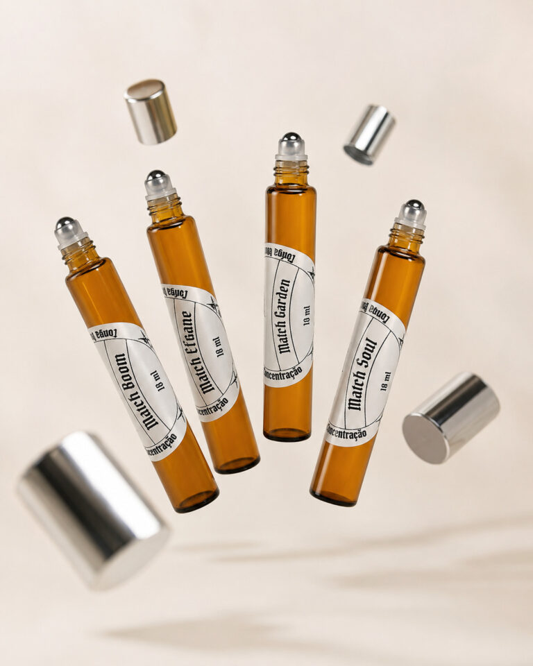 quatro frascos cilíndricos de perfume feitos em vidro âmbar com pontas redondas deslizantes em aço para aplicação de perfume com tampas prateadas flutuando