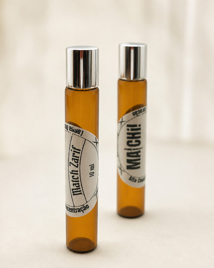 Dois frascos Âmbar com rótulos redondos com tampa cromada de perfume posicionados na vertical um na frente do outro