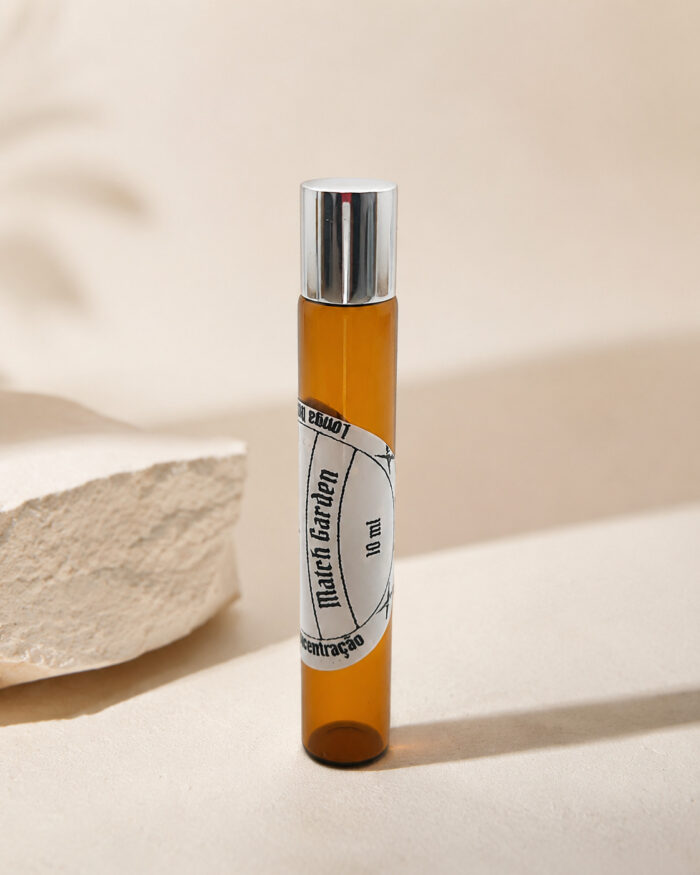 frasco cilíndrico de perfume portátil de vidro âmbar com tampa cromada rótulo branco match garden sob pedra de granito clara