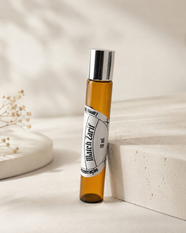 perfume masculino em frasco cilíndrico de vidro âmbar com tampa cromada sobre pedra de granito clara apoiado por outra pedra de granito claro