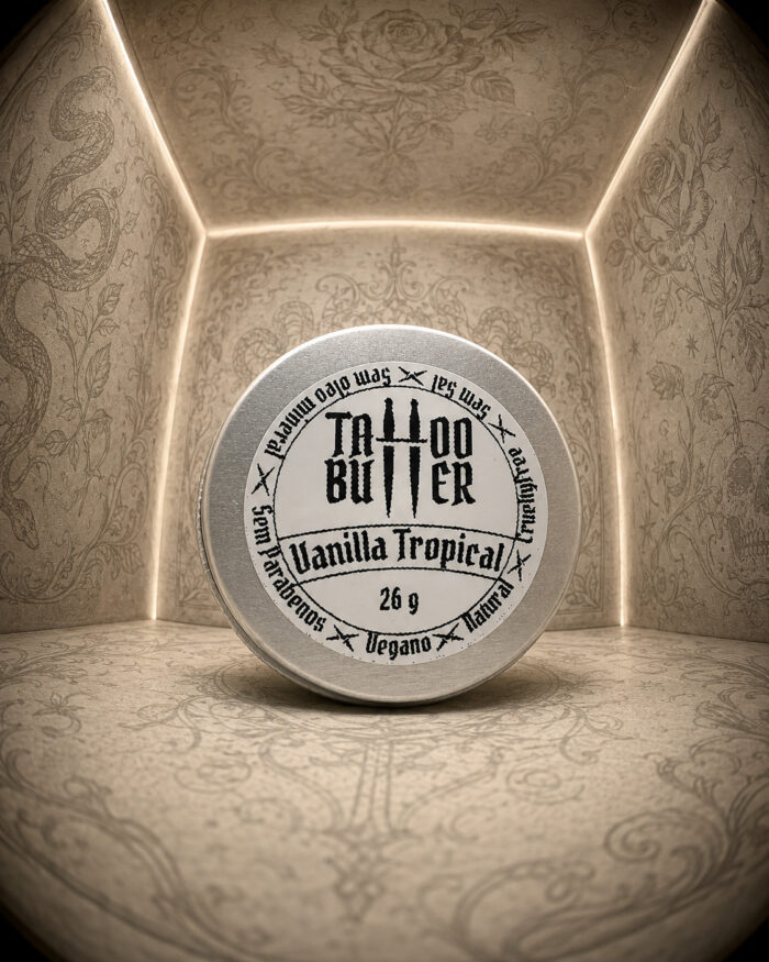 Latinha de alumínio fechada posição vertical com tampa com rótulo tattoo butter vanilla tropical 26g dentro caixa iluminada com desenhos de tatuagens